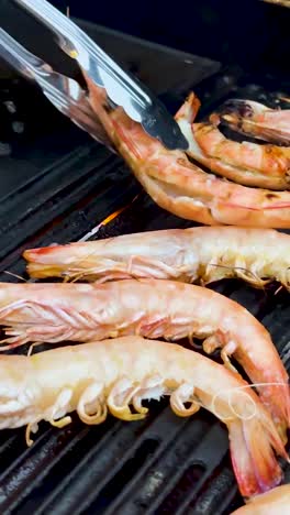 camarones siendo asados con pinzas en la barbacoa