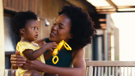 Mother-Playing-With-Young-Daughter-And-Her-Toys-Outdoors-At-Home