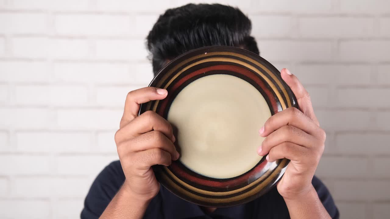 joven escondiendo la cara detrás de un plato