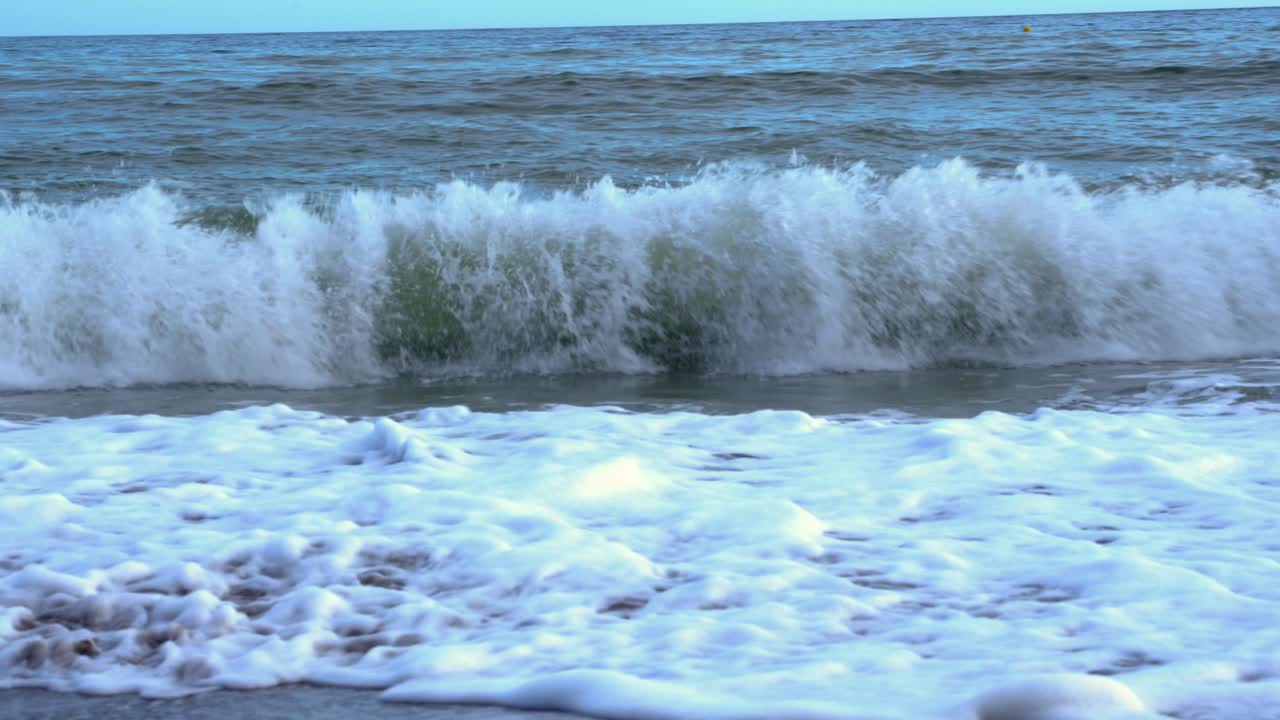 Waves breaking on the beach. Panning left