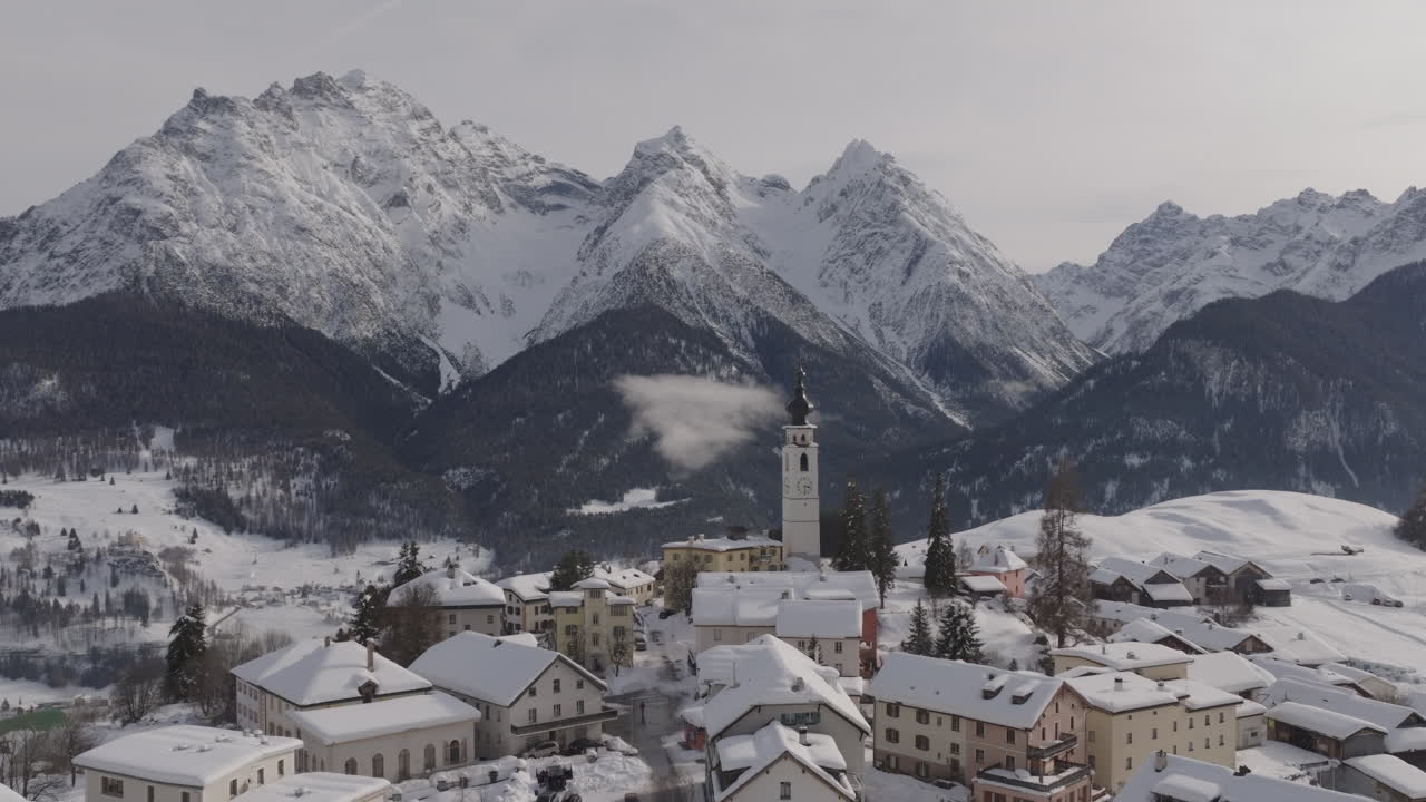 Veduta aerea cinematografica di un villaggio alpino con tetti coperti di neve e vette imponenti, che creano un sereno paesaggio invernale ideale per viaggi di lusso, turismo di alto livello e soggiorni premium.