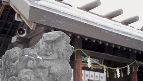 stone komainu lion-dog statue at japanese shrine in winter