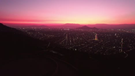 Aerial-revealing-shot-of-a-vibrant-sunset-overhead-Santiago-from-the-Mirador-Atardecer