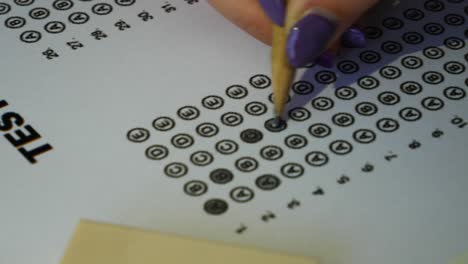 female student hand testing doing examination test with standardized test form and answers bubbled