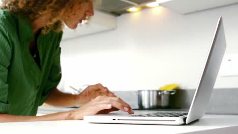 Mujer-Bonita-Usando-Una-Computadora-Portátil-En-La-Cocina