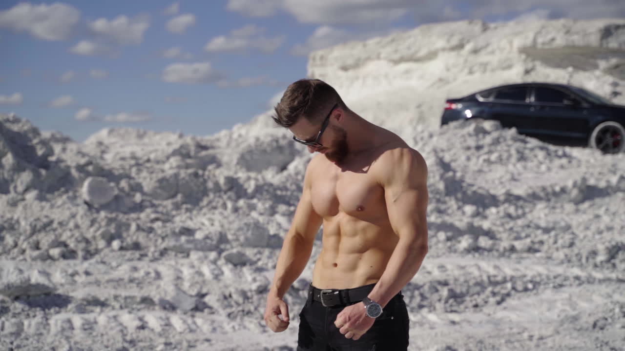 Healthy man with athletic body outdoors. Portrait of a handsome sportsman on white hill background in a sunny summer day. Sporty lifestyle.