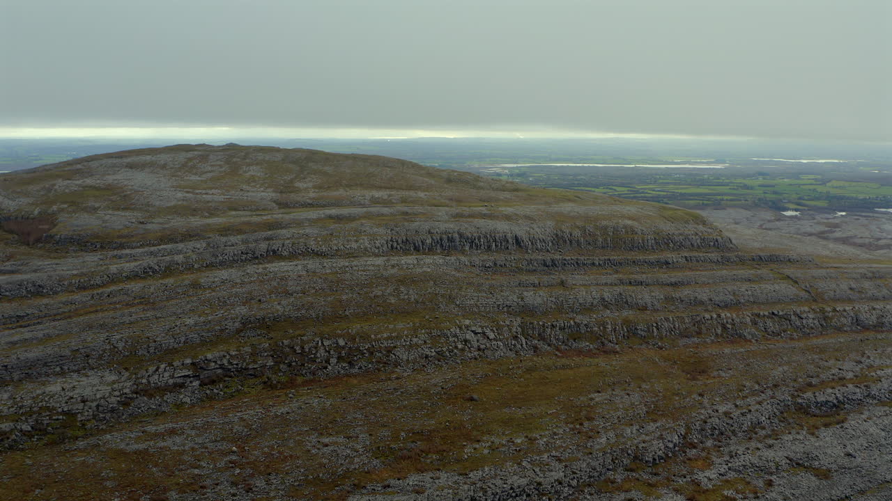Aerial drone footage orbiting Burren mountain peak, highlighting its rocky layers.