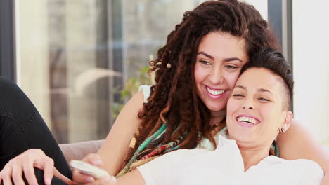 una pareja de lesbianas viendo la televisión mientras se acuestan juntos en el sofá.