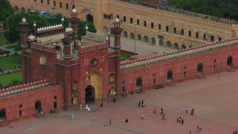 lahore, pakistán, vuelo aéreo sobre los minaretes de la mundialmente famosa mezquita badshahi, visitantes damas, caballeros y niños están en la mezquita, fieles en el suelo de la mezquita, cometas negras