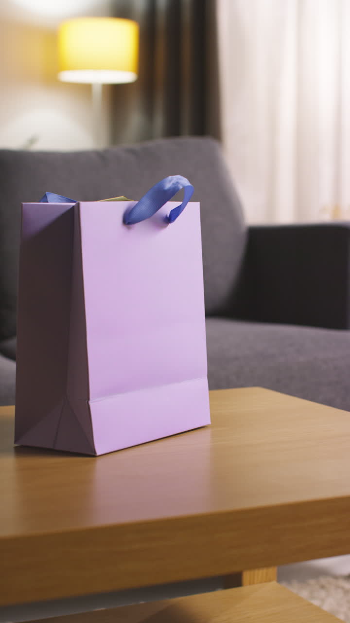 video vertical de un regalo en una bolsa de regalo en la mesa en el salón