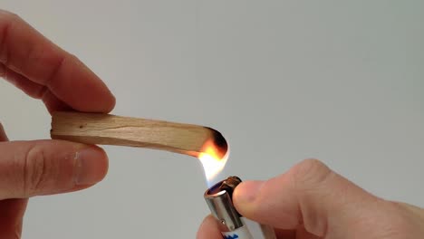 un palo de palo santo se enciende con un encendedor