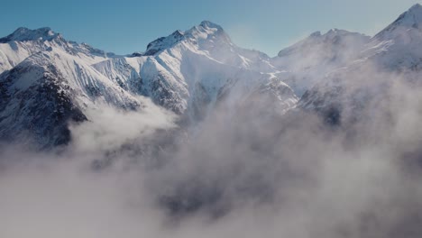 Drone-video-flying-through-the-clouds-towards-a-snowy-mountain-range