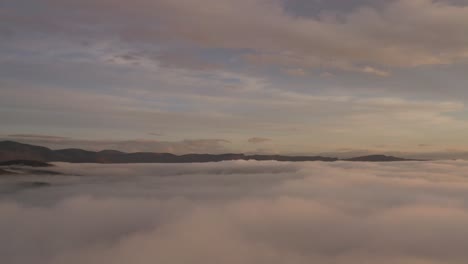 white mountains viewed from above the clouds with soft light of sunrise aerial stationary