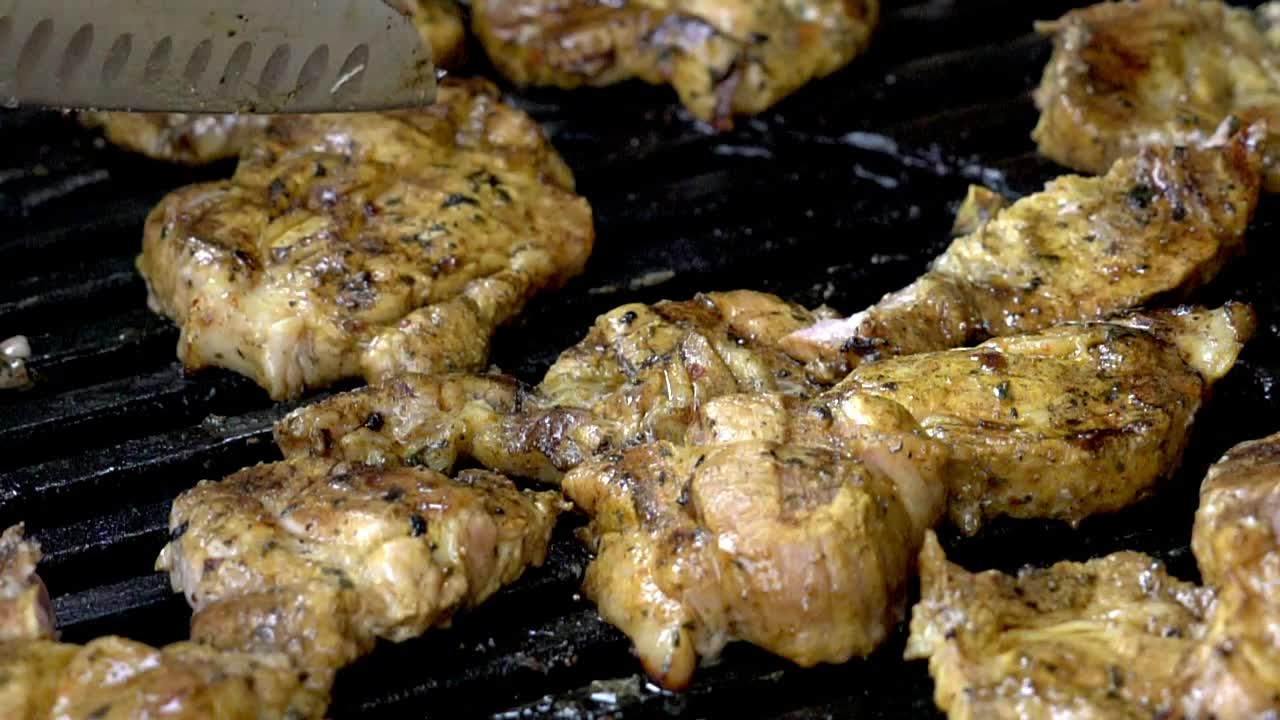 Cooking chicken on a bbq, cutting chicken pieces into smaller portions