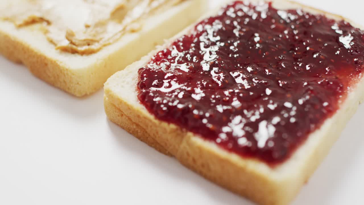 Närbild av en smörgås med jordnötssmör och sylt, med plats för text på en vit yta.