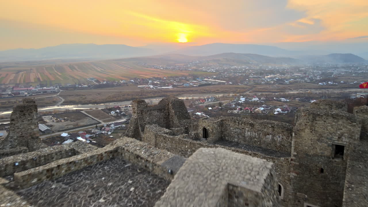 Aerial drone view of the Neamt Citadel in Targu Neamt, Romania. Fortress on the top of a hill, surrounded by lush yellowed forest, tourists, town on the background