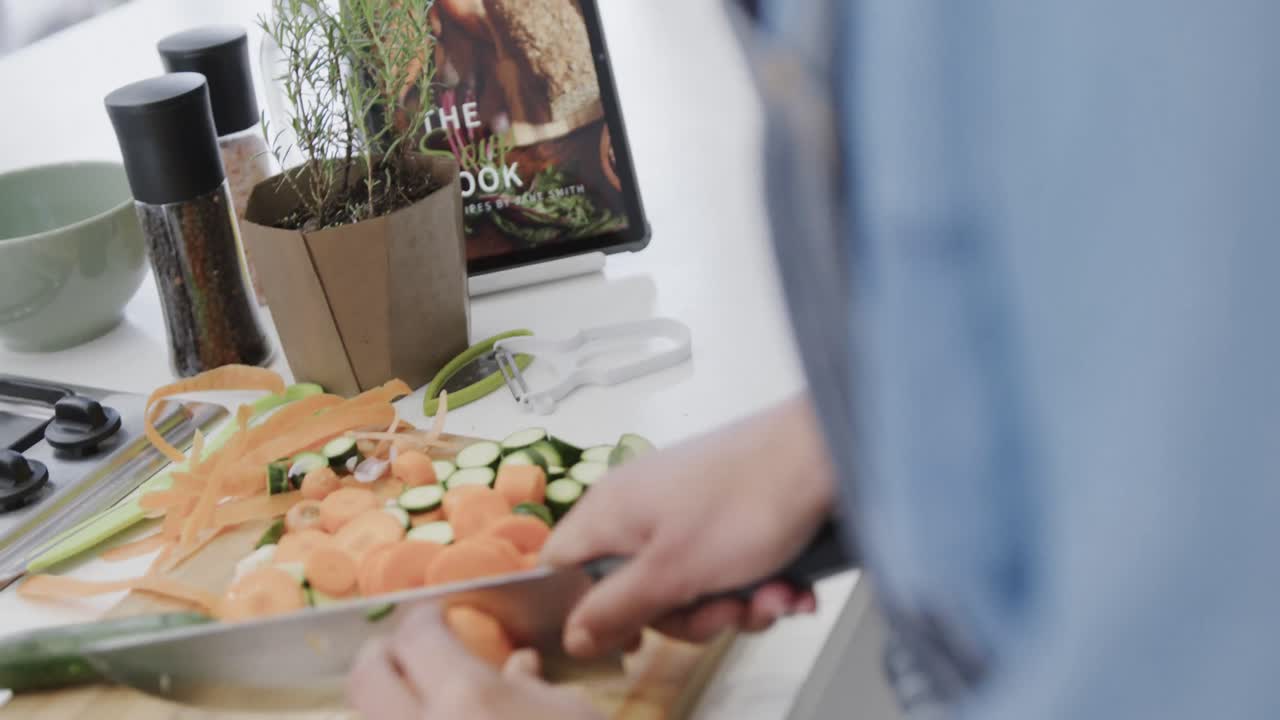 sección media de una mujer biracial preparando comida, cortando verduras en la cocina, cámara lenta