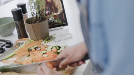 midsection of biracial woman preparing meal, chopping vegetables in kitchen, slow motion