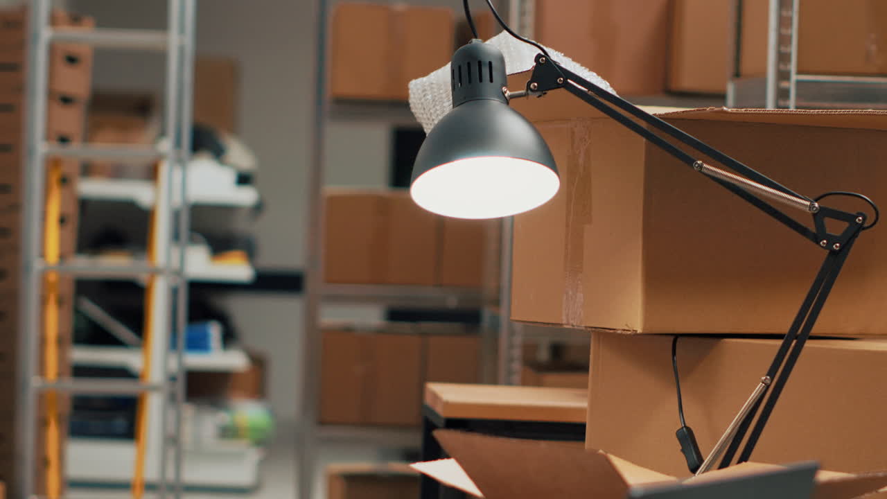 Warehouse office with cardboard boxes, laptop, and lamp
