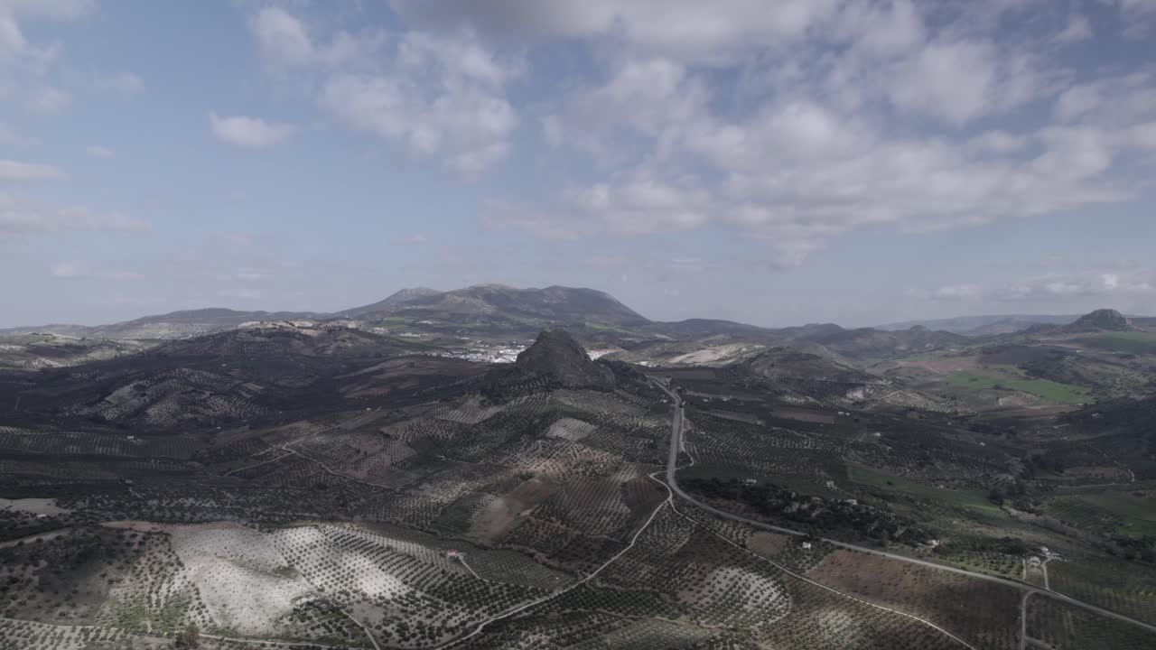 Aerial 4K footage of Olvera, Spain, captured with a DJI drone at 30fps. A cinematic view of open meadows with a stunning castle atop the mountain in the background.
