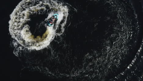 aerial top down view of a young male on a jet ski driving in circles in the water in sweden