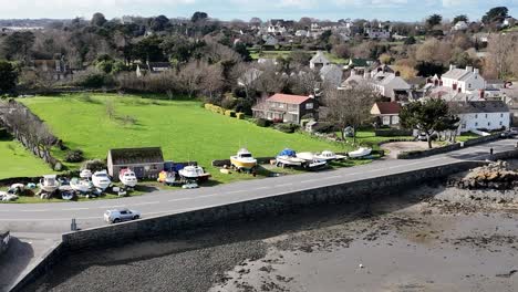 Un-Dron-En-Círculos-Cercanos-Disparó-En-Un-Día-Brillante-En-El-Puerto-De-Burdeos,-Guernsey,-Mostrando-El-Almacenamiento-En-La-Carretera-Y-En-Botes-Y-Vistas-A-Los-Campos-Hasta-St.-Sampson.