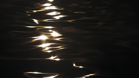 sunset wave sparkling reflection slow motion on ocean surface pan up to a silhouette boat like a movie credit