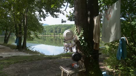 off grid camping scene near to lake with personal items hung on trees