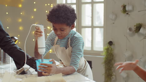 Niño-Pequeño-Que-Usa-Una-Batidora-De-Mano-Durante-La-Clase-De-Cocina