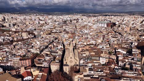 Toma-Aérea-De-Establecimiento-De-La-Histórica-Basílica-De-Sant-Francesc-Y-El-Paisaje-Urbano-De-Palma-De-Mallorca-Iluminada-Por-El-Sol,-España