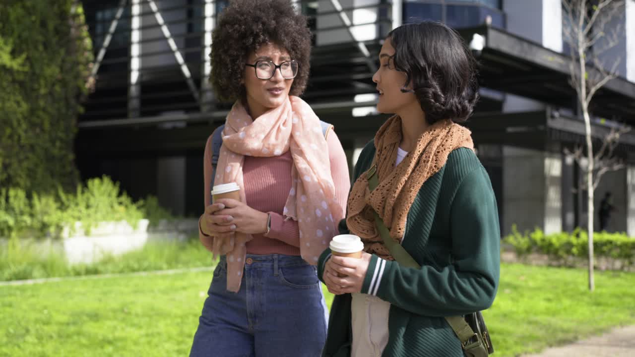 Diverse female friends with coffee cups, backpack, bag walking on campus, planning route