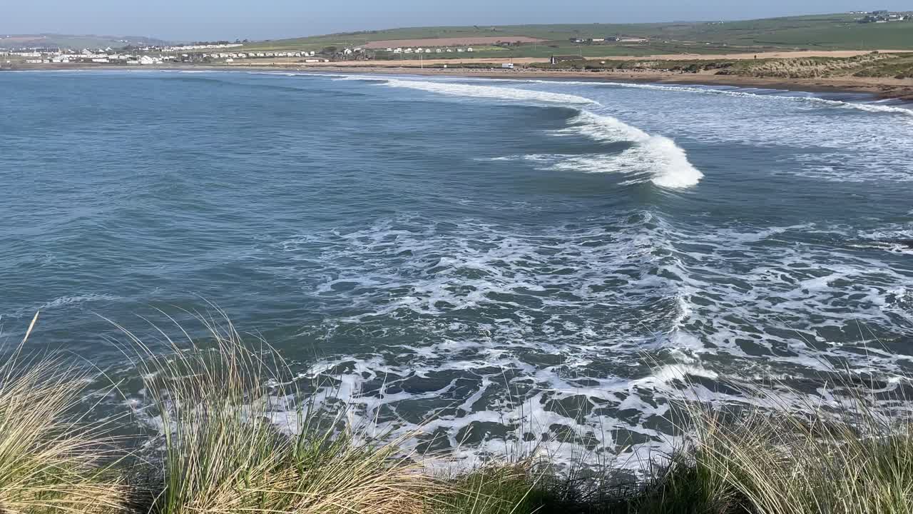 día brumoso en la costa irlandesa con oleaje creando arcoíris en las crestas de las olas