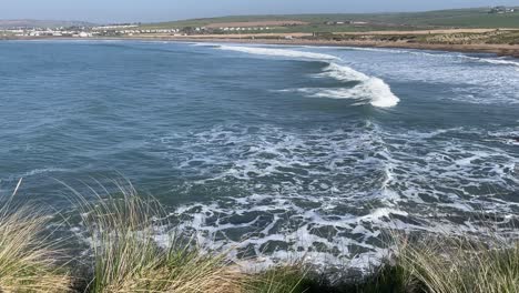 hazy day on the irish coast with swell creating rainbows in wave crests