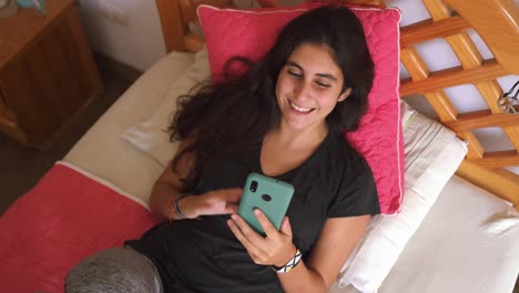 Mujer-Joven-Riendo-Haciendo-Video-Chat-Usando-El-Teléfono-Móvil-En-La-Cama