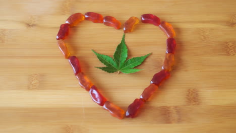 cbd gummy picked from heart of edible candies, marijuana leaf in center