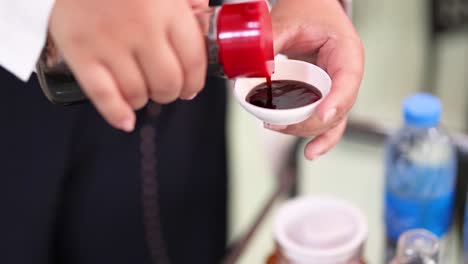 persona vertiendo salsa en una taza pequeña