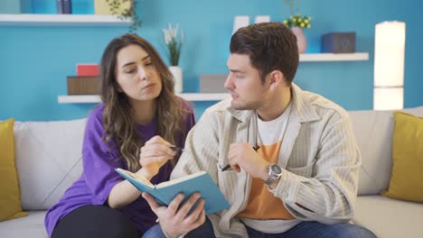 Young-man-holding-a-notebook-and-asking-something-to-his-lover-young-woman.