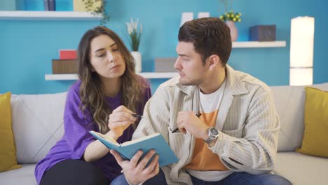 hombre joven sosteniendo un cuaderno y preguntando algo a su amante mujer joven.