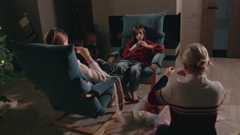 family knitting together by the fireplace during christmas