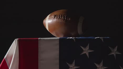 low key lighting studio shot of american football on stars and stripes flag 7