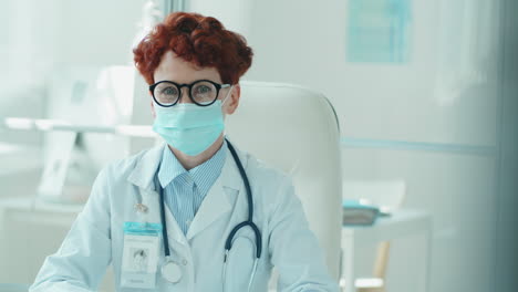 retrato de una joven médica con máscara en el escritorio de la clínica