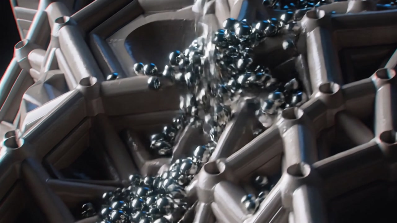 Pouring from narrow tube, stream of metal spheres striking honeycomb tray, filling pockets