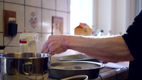 A-woman-chef-coating-round-baking-pans-with-flour-to-prevent-sticking-as-she-bakes-vegan-chocolate-cake-for-dessert-in-a-kitchen