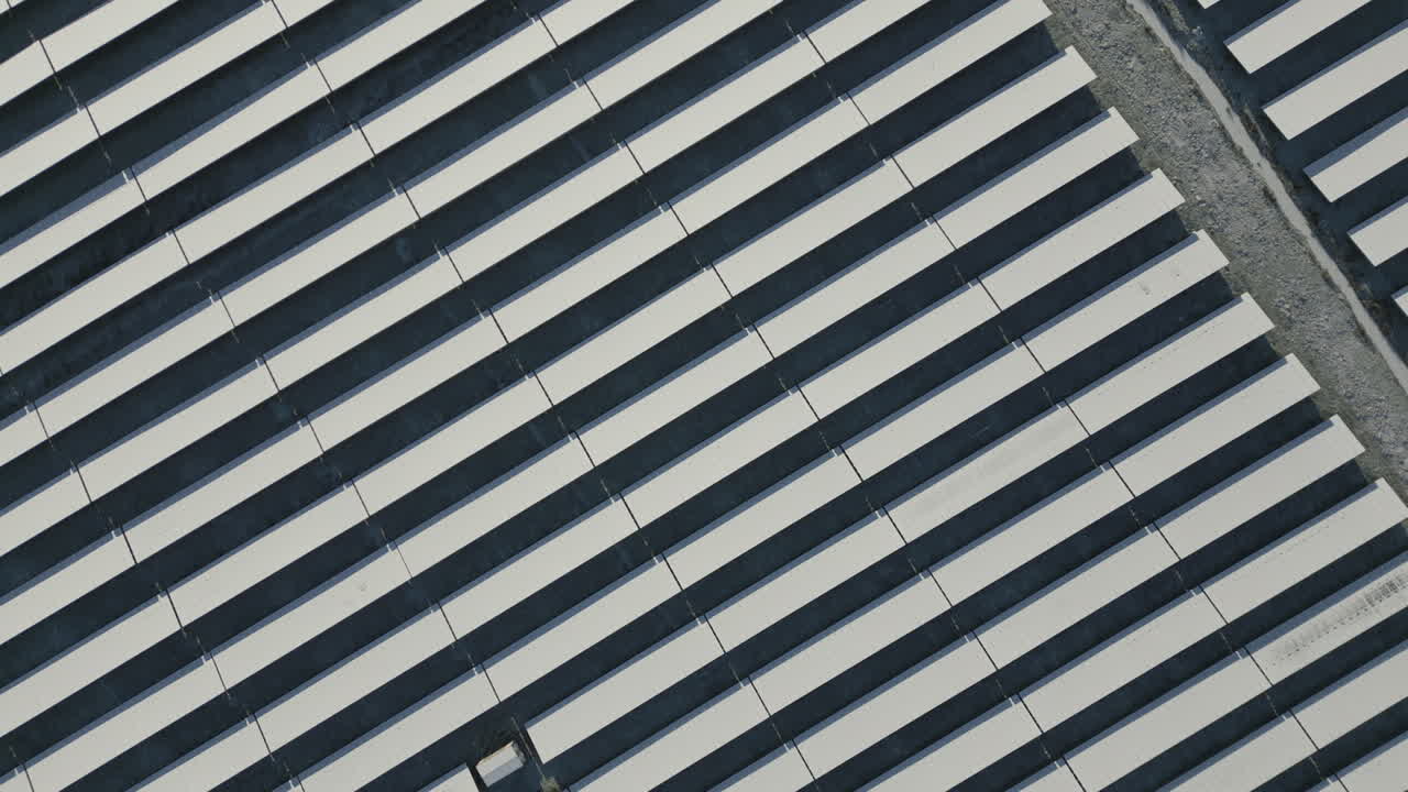 Solar panels of solar power plant covered in snow and ice, diagonal lines, top down drone shot, slow movement forward