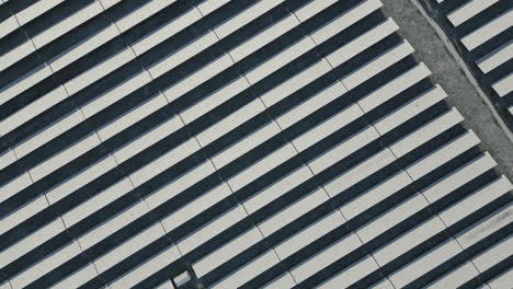 solar panels of solar power plant covered in snow and ice, diagonal lines, top down drone shot, slow movement forward