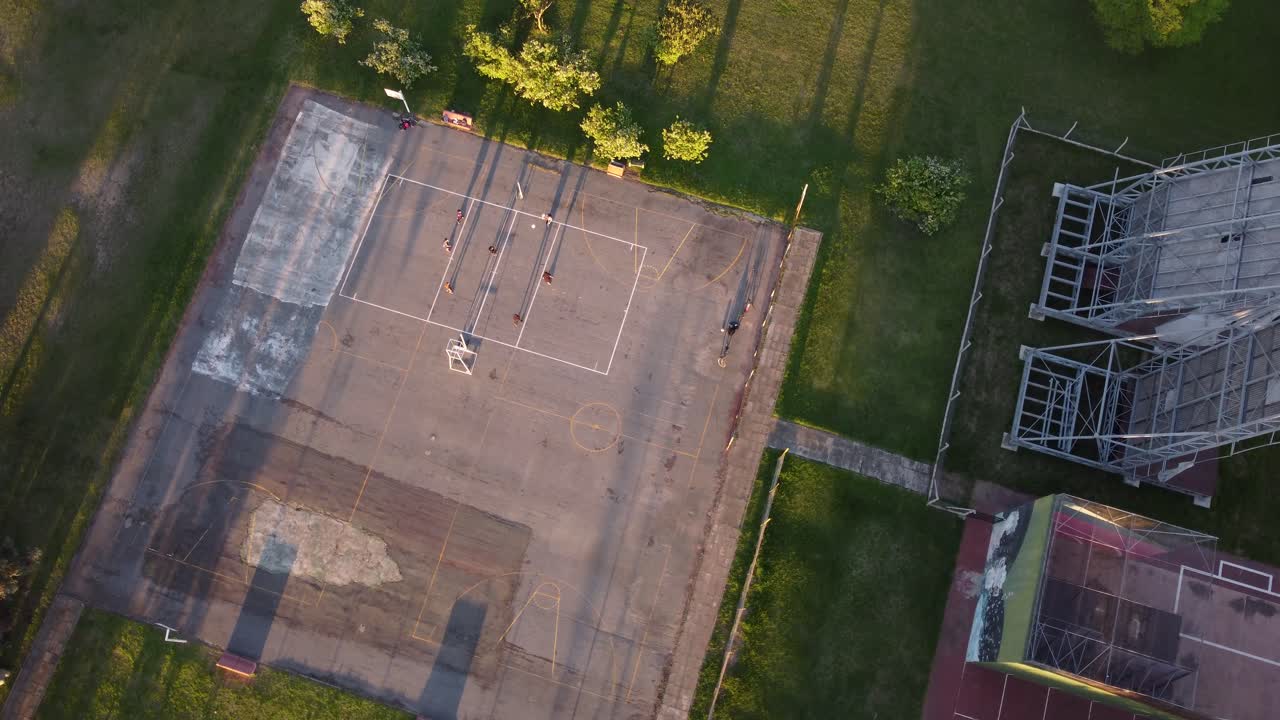 Ariel view of friends playing volleyball at a park at sunset with native trees around it, in Buenos Aires, Argentina