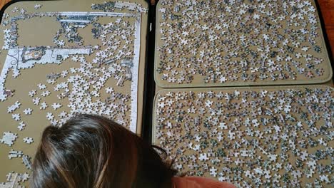 Top view of a woman on comfortable clothes at hme working on a big puzzle