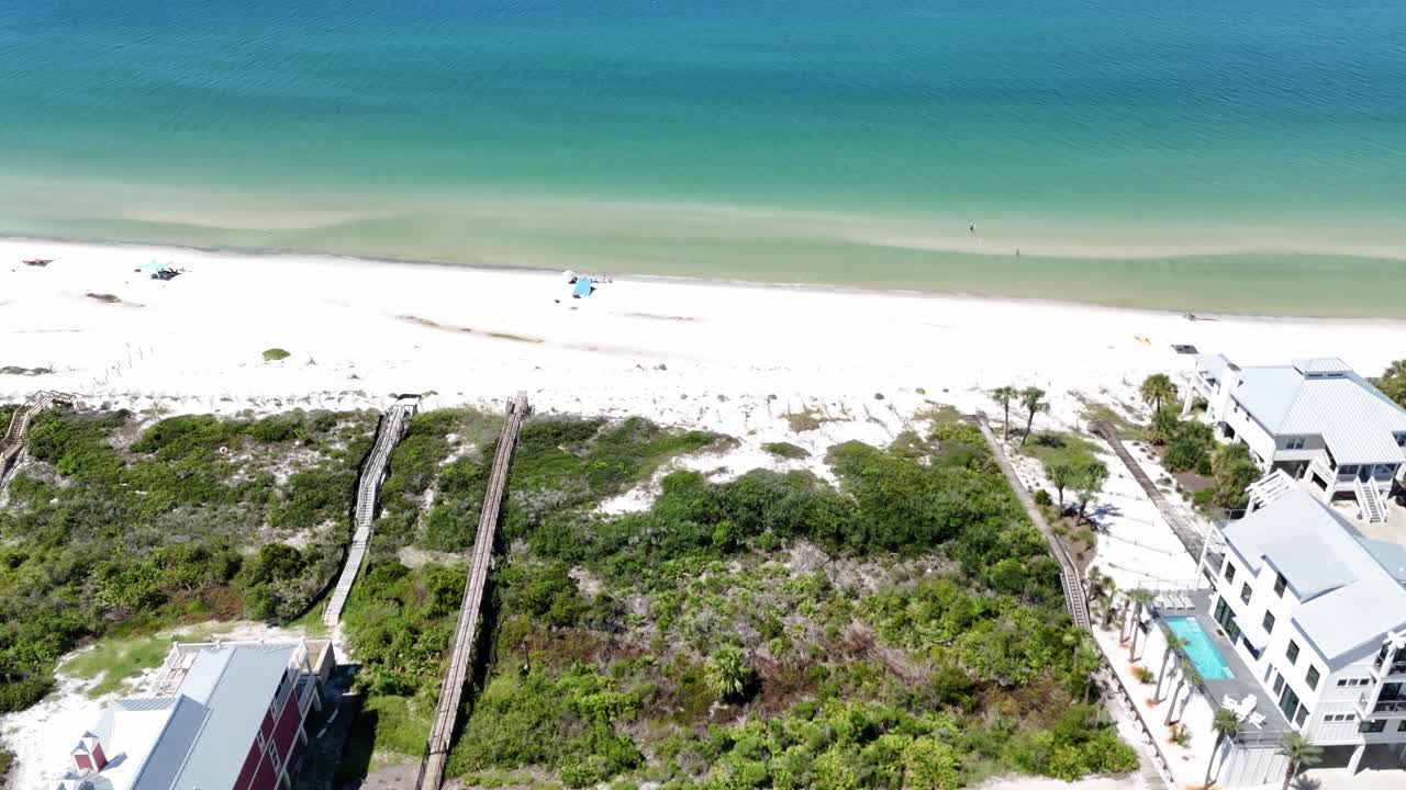 Vertically tilted drone fly over sandy beach and ocean with waterfront houses and greenery, Cape San Blas, Gulf County, Florida, USA