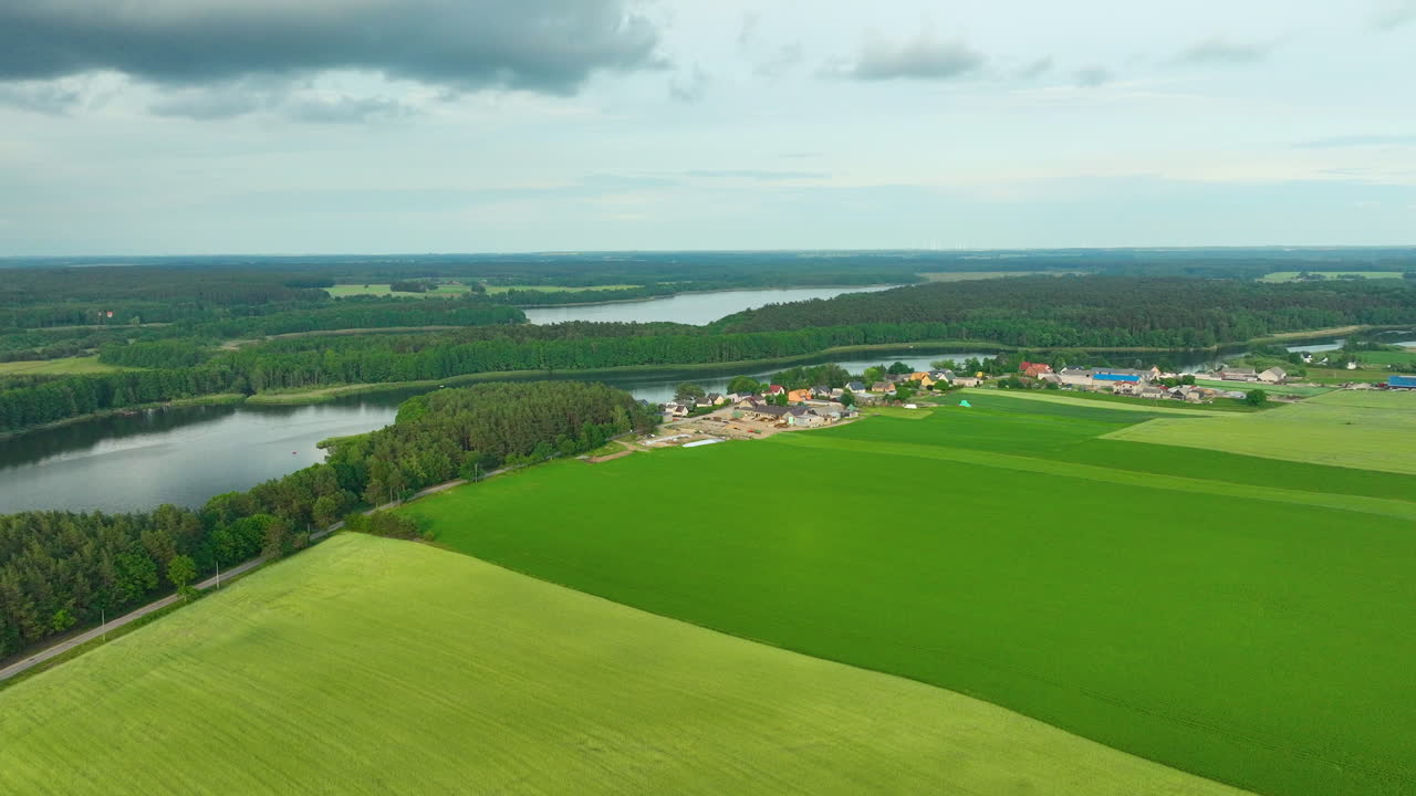 vista aérea de una aldea junto a un río rodeada de exuberantes campos verdes y bosques