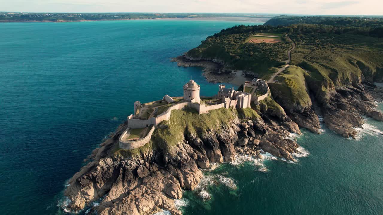 Ripresa con drone intorno a Fort La Latte, Castello de la Roche Guyon a Cap Frehel, Bretagna, Francia, in una giornata di sole d'estate con le onde che si infrangono sulle scogliere di arenaria